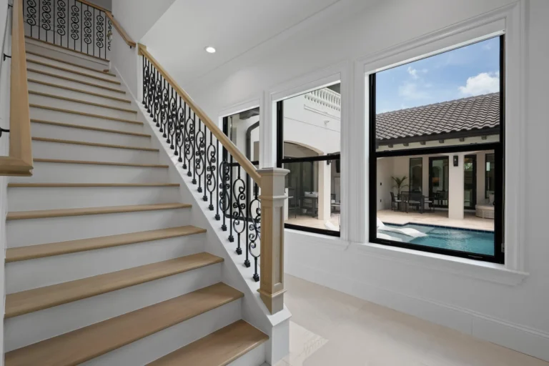Staircase with wrought iron railing overlooking the pool in a Halo Industrial custom home